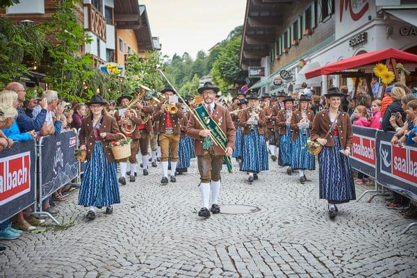 Österreichischer Festumzug mit Musikern in Tracht durch das Dorf Saalbach