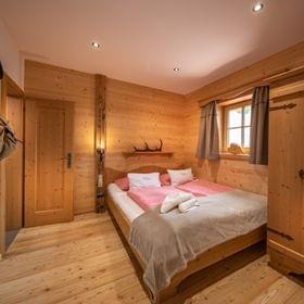 Gemütliches Alpen-Schlafzimmer mit Holzmöbeln und Doppelbett in rustikaler Berghütte