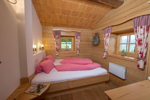 Cozy alpine wooden bedroom with red check bedding and traditional curtains