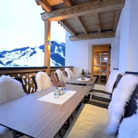 Cozy alpine terrace with fur-covered chairs and snowy mountain view
