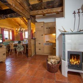 Cozy Alpine cabin interior with wood-burning stove, rustic furniture, and traditional kitchen