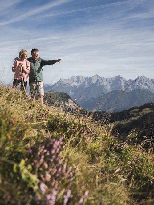 Seniorenpaar wandert auf Alpinem Pfad mit Panoramablick auf die Berge im Sommer