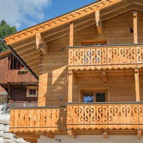 Traditional alpine wooden chalet with decorative balconies in sunny mountain setting