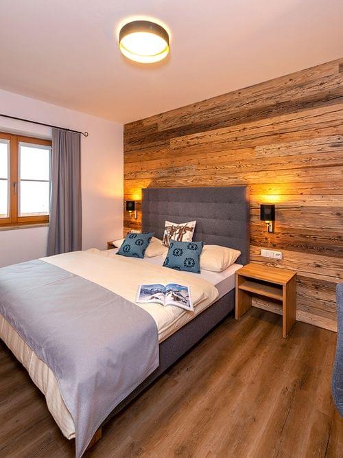 Modernes Hotelzimmer mit Doppelbett, Holzakzentwand und Flachbildfernseher