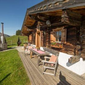 Rustikale Alpenhütte aus Holz mit Blumenkästen und Bergblick an einem sonnigen Tag