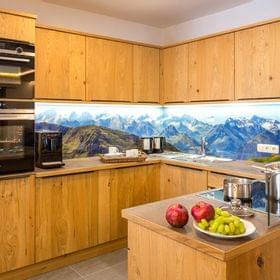 Modern wooden kitchen with built-in appliances and mountain landscape backsplash