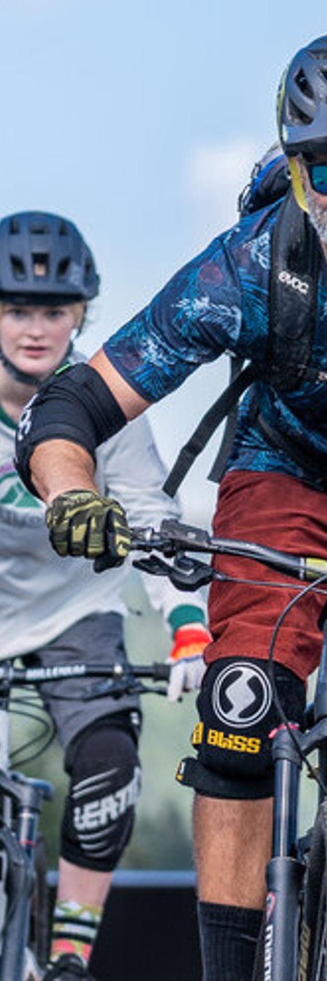 Zwei Mountainbiker fahren einen Trail in alpiner Landschaft hinunter