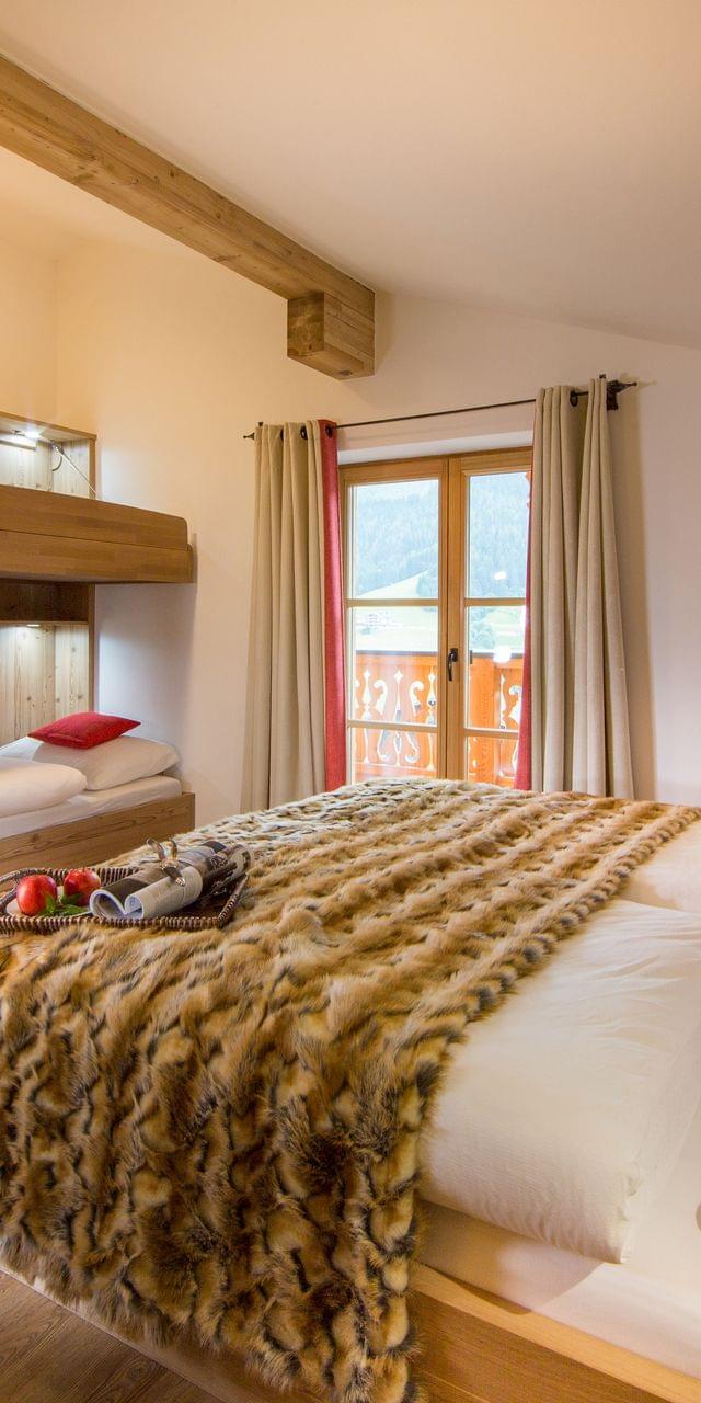 A cozy alpine-chic room with a double bed and a bunk bed.