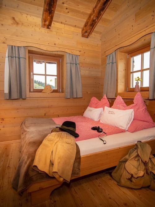 Gemütliches Alpenzimmer mit Holzmöbeln, rosa Karo-Bettwäsche und traditioneller Dekoration