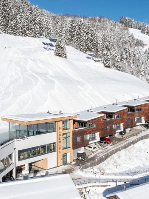 Das Bachgut aus der Vogelperspektive, Winterliche Berge und die Chalets mit dem Badehaus und Invinity-Pool