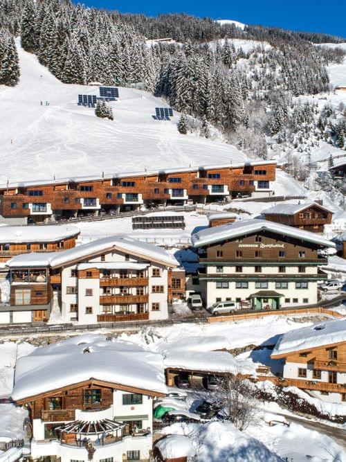 Alpines Skidorf mit Holzhütten und verschneiten Pisten im Winter