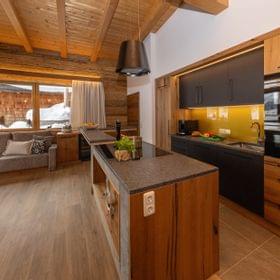 Gemütliche Alpenküche und Wohnzimmer mit Holzeinrichtung und Winterblick durch große Fenster