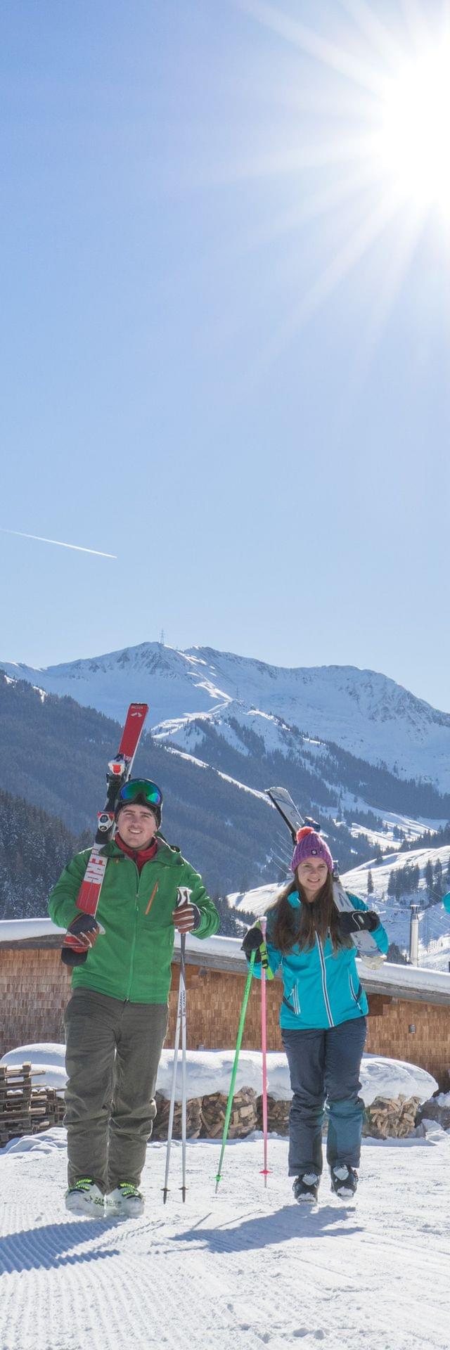 Group of skiers walking on snowy slope with alpine village and mountains in background