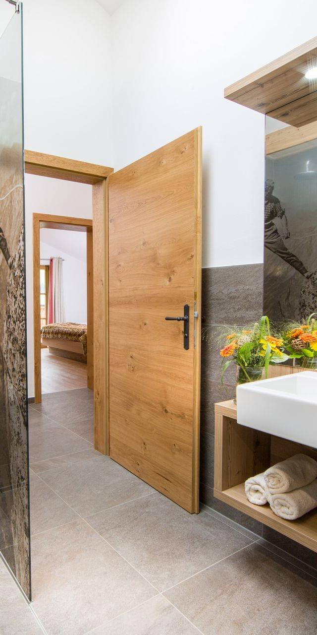 Modern hotel bathroom with walk-in shower, wooden accents, and fresh towels