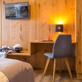 Cozy hotel room with wooden wall, flat-screen TV, ski gear, and desk with reading lamp