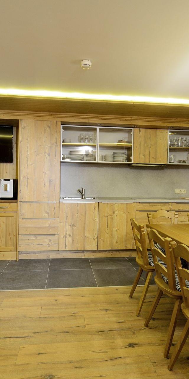 Modern alpine kitchen with wooden cabinets, long dining table, and built-in appliances