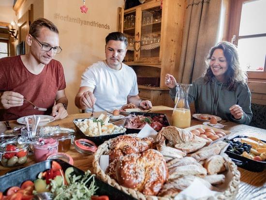 3 Freunde die am Gedecktem Tisch sitzen und Frühstücken 