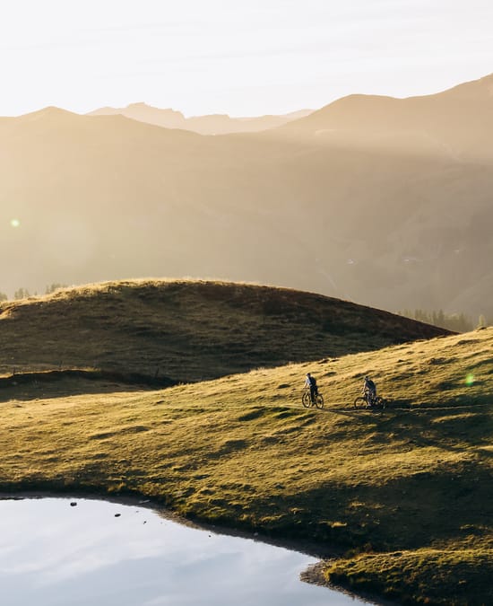 A mountain biker on a trail on the mountain, with an autumnal atmosphere and the sun setting.