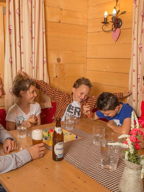 Family enjoying board game and drinks in cozy alpine cabin with mountain view