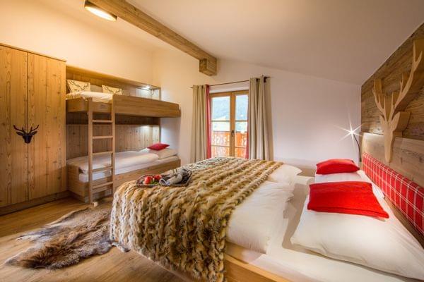 A cozy alpine-chic room with a double bed and a bunk bed.